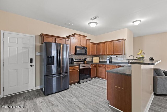 248 Seville St, Jacksonville, NC 28546 - kitchen with appliances with stainless steel finishes, a sink, a peninsula, light wood finished floors, and brown cabinetry