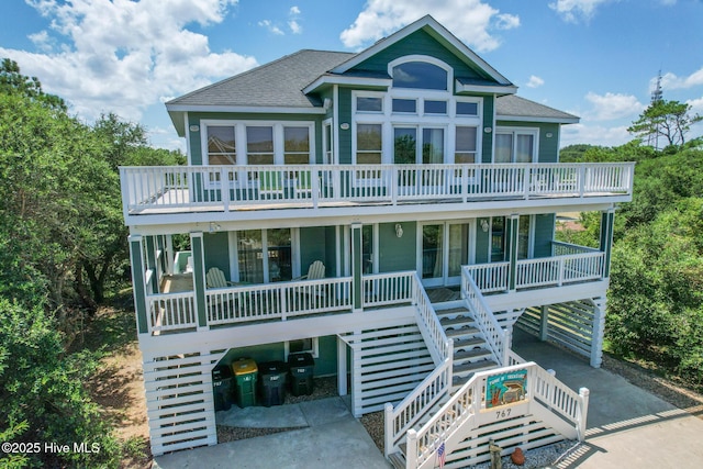 view of front of property with driveway, a shingled roof, stairs, and a carport