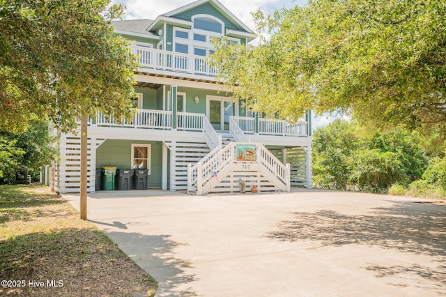 view of front of home featuring a porch, driveway, stairway, and a carport