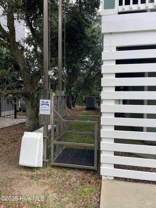 details featuring fence, a gate, and central air condition unit