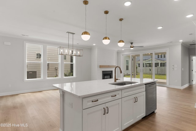 kitchen featuring crown molding, a fireplace, dishwasher, a sink, and open floor plan