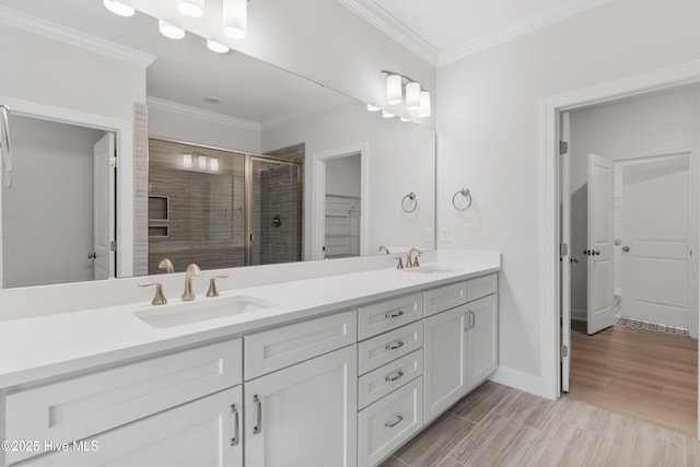 bathroom with crown molding, double vanity, a shower stall, and a sink