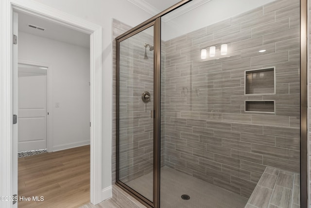 bathroom featuring baseboards, a shower stall, wood finished floors, and visible vents