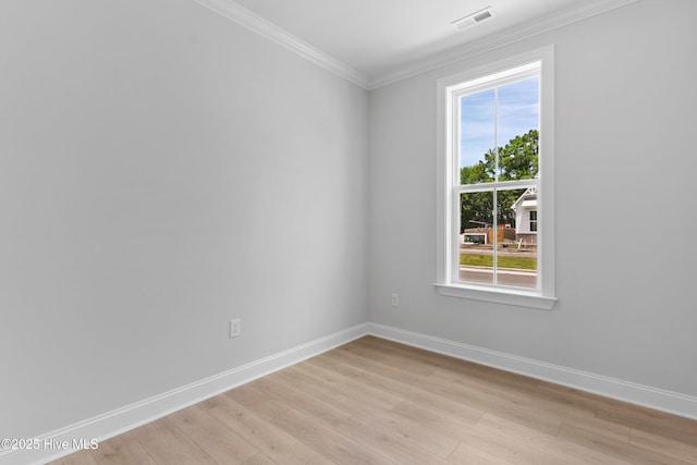 spare room featuring visible vents, light wood finished floors, crown molding, and baseboards