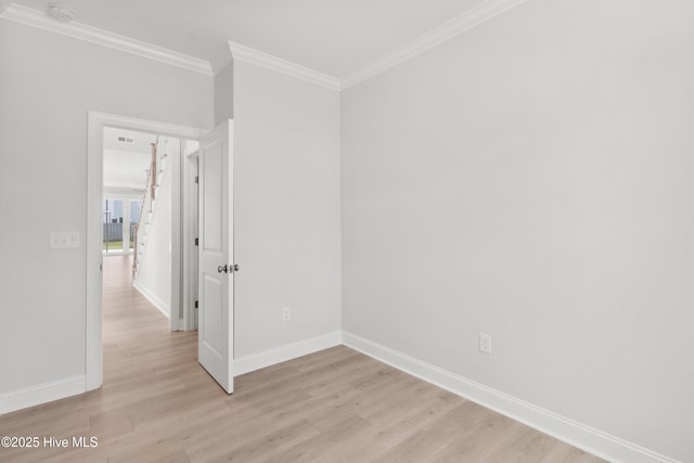 spare room with baseboards, ornamental molding, and light wood-style floors