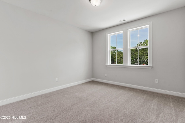 spare room featuring carpet floors, baseboards, and visible vents