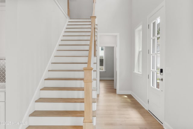 interior space featuring baseboards, light wood finished floors, stairs, and a wealth of natural light