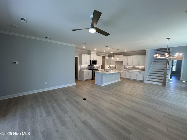 3157 Painted Turtle Loop Unit 37, Wilmington, NC 28409 - unfurnished living room featuring a chandelier, a ceiling fan, crown molding, stairs, and light wood-style floors
