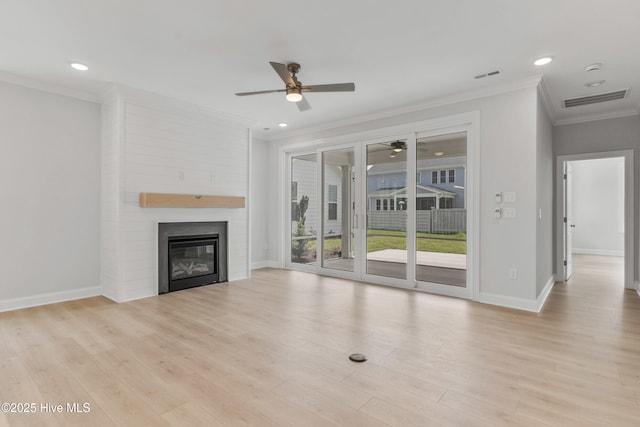 unfurnished living room with ceiling fan, a large fireplace, light wood-style flooring, visible vents, and ornamental molding