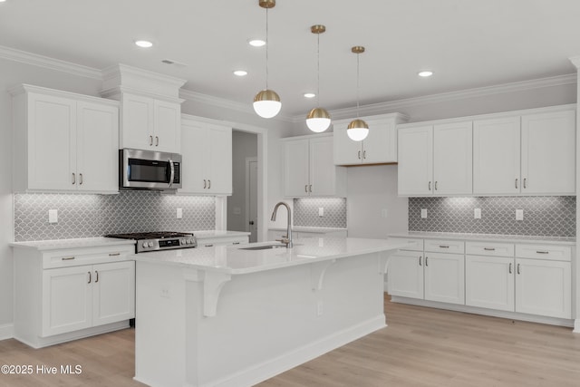kitchen with a sink, stainless steel microwave, a kitchen island with sink, and white cabinets