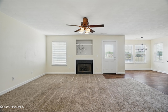101 Whitetail Ct, South Mills, NC 27976 - unfurnished living room with dark colored carpet, baseboards, ceiling fan with notable chandelier, and a fireplace