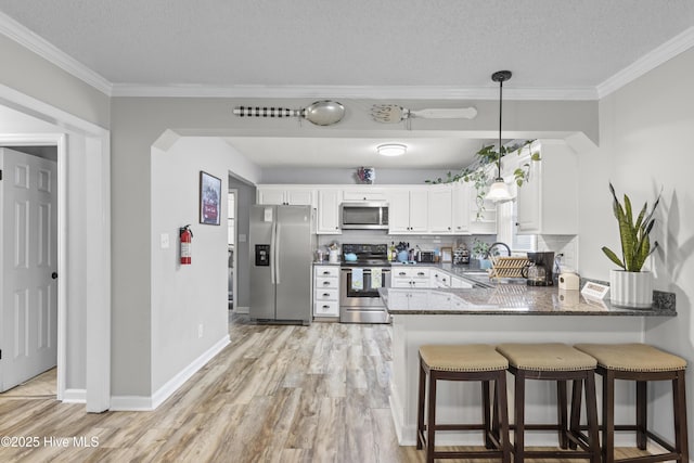 803 Oakwood Ave, Jacksonville, NC 28546 - kitchen featuring a sink, stainless steel appliances, a peninsula, light wood-type flooring, and ornamental molding
