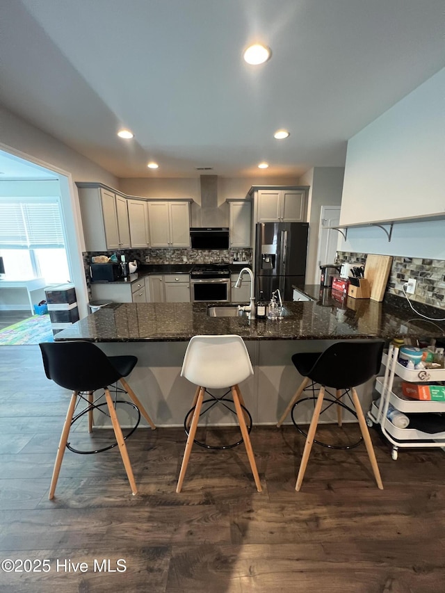 kitchen featuring a sink, fridge with ice dispenser, gray cabinets, and a kitchen bar
