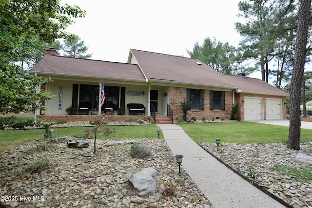 view of front of house featuring a chimney, an attached garage, a front lawn, brick siding, and driveway