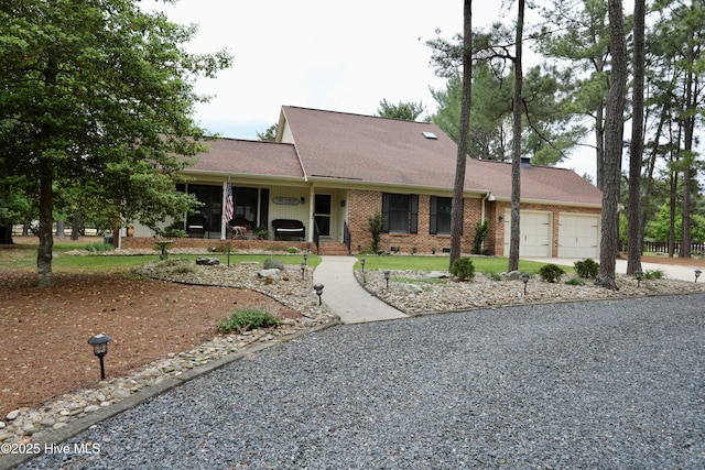 single story home with a garage, brick siding, and driveway