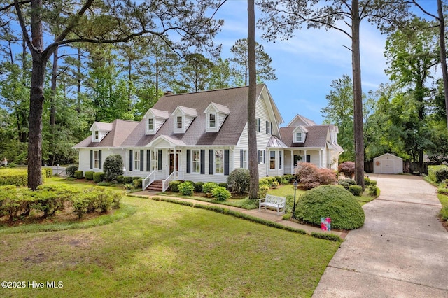 view of front facade featuring driveway, a front lawn, an outbuilding, and a detached garage