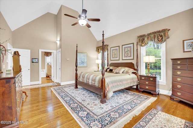 bedroom featuring light wood finished floors, baseboards, high vaulted ceiling, and ceiling fan
