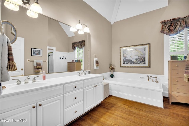 full bath featuring vaulted ceiling, wood finished floors, plenty of natural light, a stall shower, and a garden tub