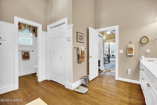 ensuite bathroom with wood finished floors, a high ceiling, baseboards, toilet, and vanity