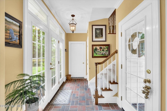 entryway featuring brick flooring, ornamental molding, stairway, and baseboards