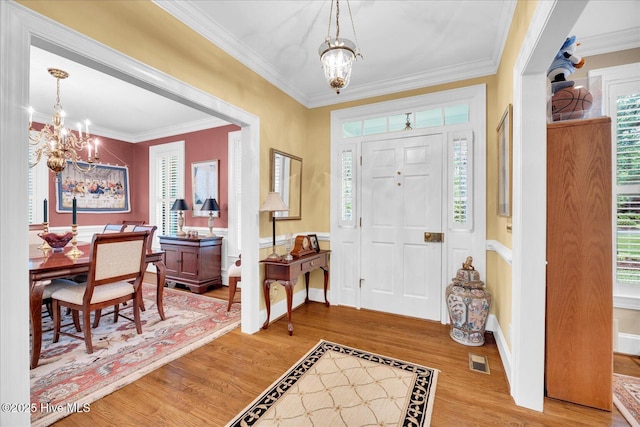 entryway with a chandelier, wood finished floors, crown molding, and baseboards