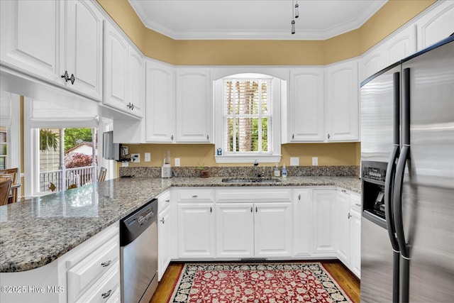 kitchen featuring appliances with stainless steel finishes, a sink, wood finished floors, healthy amount of natural light, and crown molding