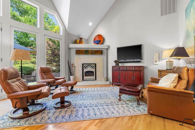 living area featuring high vaulted ceiling, visible vents, and wood finished floors