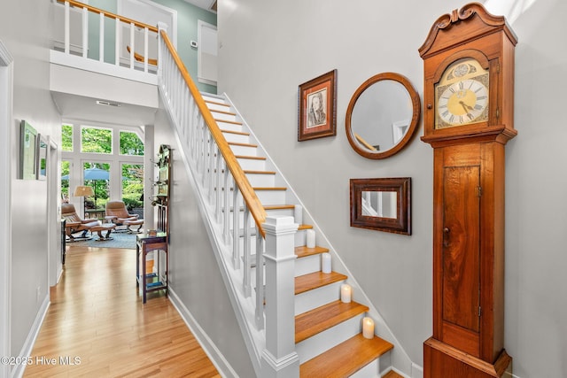 stairway with baseboards, wood finished floors, and visible vents