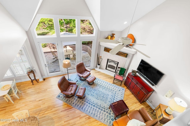 living area featuring baseboards, a ceiling fan, wood finished floors, and a fireplace