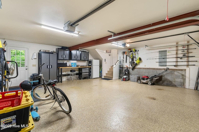 garage featuring freestanding refrigerator and a garage door opener
