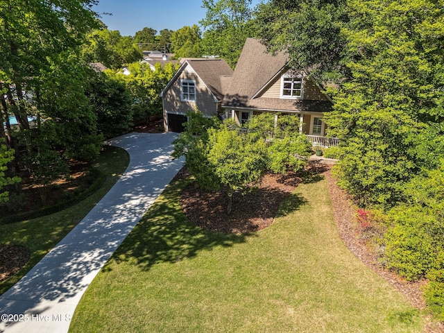 view of front of property featuring concrete driveway, an attached garage, and a front lawn