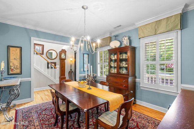 dining area featuring an inviting chandelier, crown molding, baseboards, stairway, and light wood-style flooring