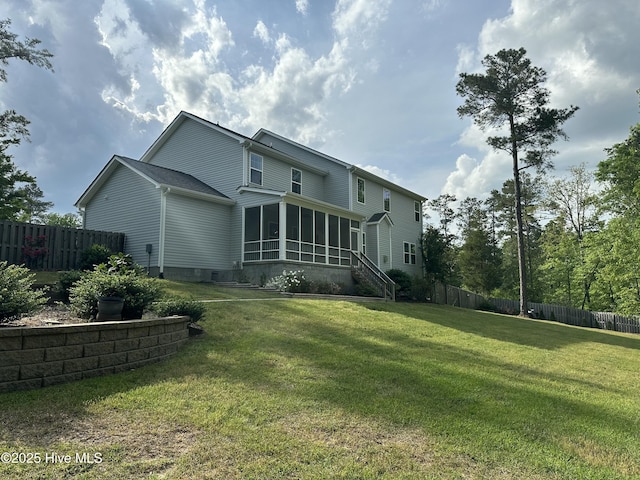 back of property featuring fence, a lawn, and a sunroom