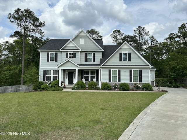 view of front facade featuring covered porch, fence, and a front yard