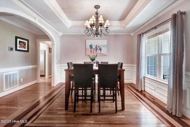 1171 Airport Rd, Pikeville, NC 27863 - dining area featuring an inviting chandelier, a raised ceiling, arched walkways, wood finished floors, and visible vents
