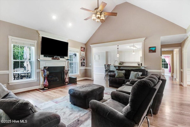 1171 Airport Rd, Pikeville, NC 27863 - living area featuring light wood-style floors, a ceiling fan, a fireplace with raised hearth, and high vaulted ceiling