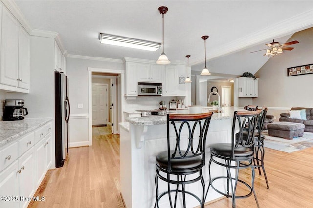 1171 Airport Rd, Pikeville, NC 27863 - kitchen with white cabinets, light wood-style floors, a breakfast bar area, stainless steel appliances, and a ceiling fan