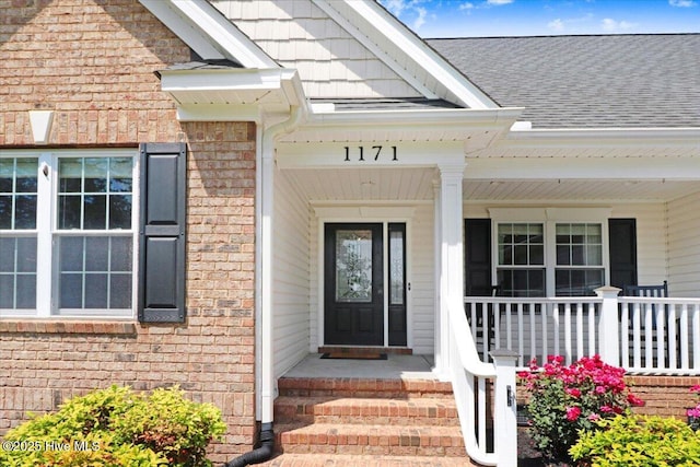 1171 Airport Rd, Pikeville, NC 27863 - view of exterior entry featuring a shingled roof, a porch, and brick siding