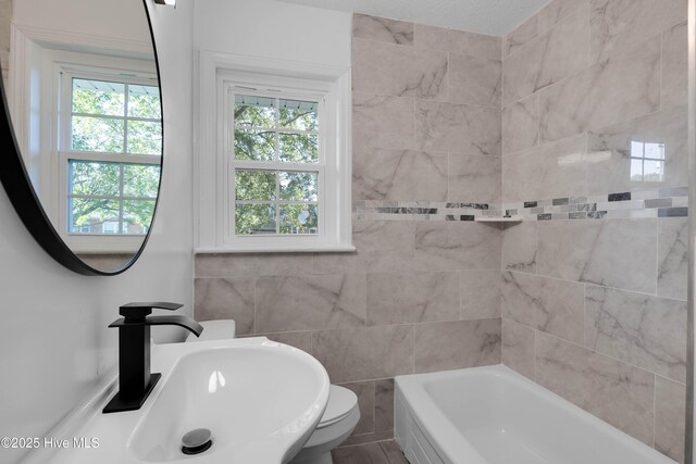 full bath featuring a sink, tile walls, and toilet