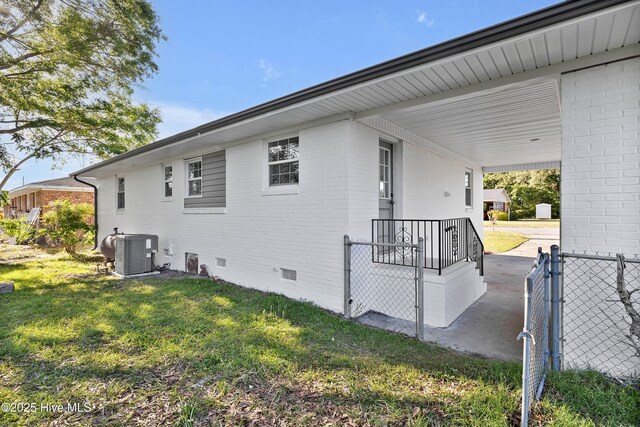 view of home's exterior featuring crawl space, a lawn, brick siding, cooling unit, and fence