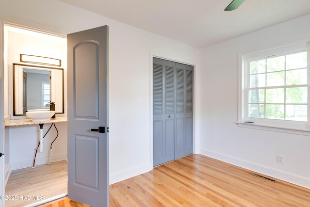 unfurnished bedroom with baseboards, visible vents, light wood-style flooring, and a closet