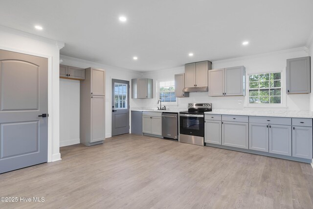kitchen featuring light countertops, gray cabinets, stainless steel appliances, under cabinet range hood, and ornamental molding