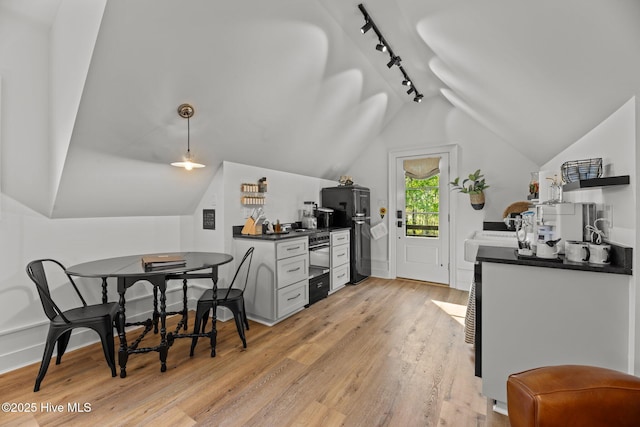 628 E Harborside Rd, Oriental, NC 28571 - kitchen with freestanding refrigerator, lofted ceiling, rail lighting, dark countertops, and light wood-type flooring