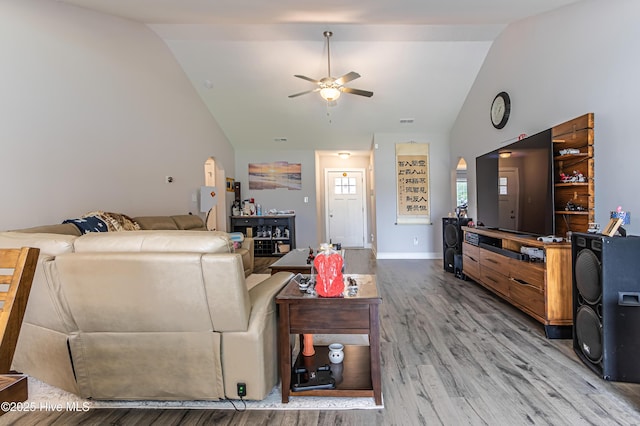 living area with arched walkways, ceiling fan, wood finished floors, and lofted ceiling