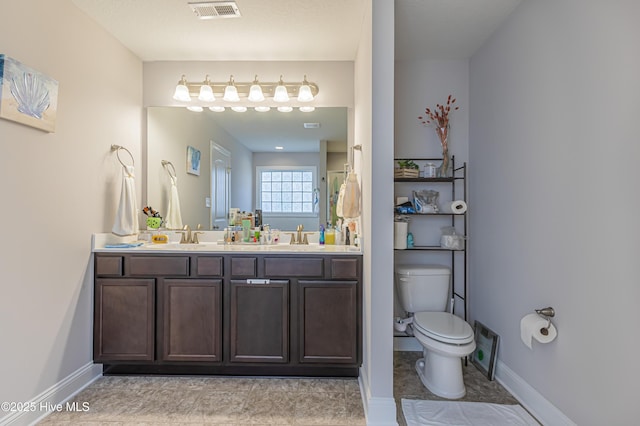 bathroom with double vanity, visible vents, a sink, baseboards, and toilet