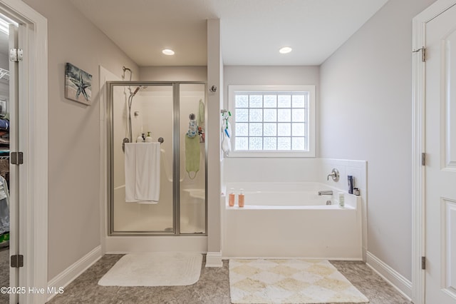bathroom featuring baseboards, a spacious closet, a bath, and a stall shower