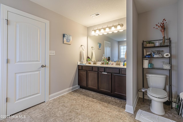 full bath with a sink, double vanity, toilet, baseboards, and visible vents
