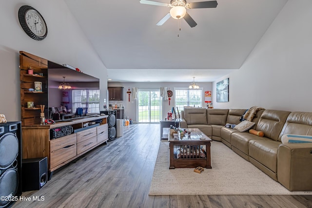 living room with wood finished floors, ceiling fan with notable chandelier, and lofted ceiling