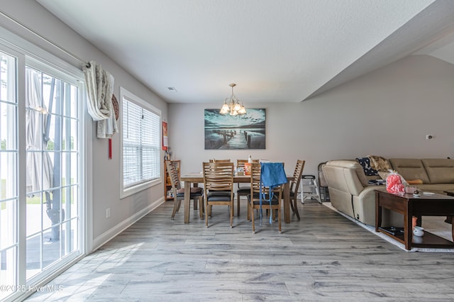 dining area featuring baseboards, light wood-style flooring, lofted ceiling, and a chandelier