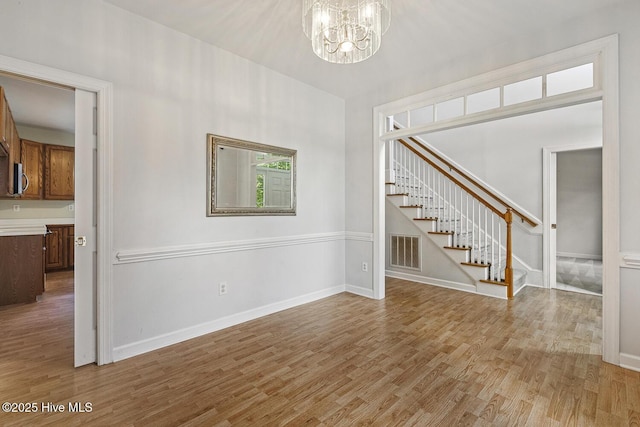 1601 Castalia Dr, Cary, NC 27513 - unfurnished room with a chandelier, light wood-style flooring, stairs, and baseboards
